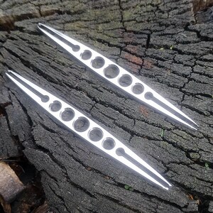 Puede incluir: Dos pinzas de plata con una punta puntiaguda y varios agujeros a lo largo de la longitud de las pinzas.