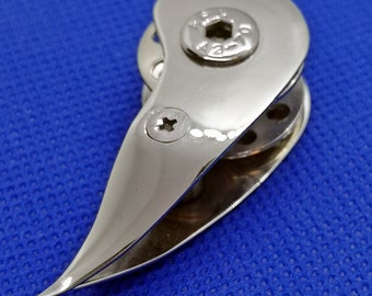 Op de afbeelding: Een zilverkleurige metalen bootklem met een afgerond, puntig uiteinde en een kleine schroef aan de zijkant. De klem heeft een klein, rond gat in het midden.