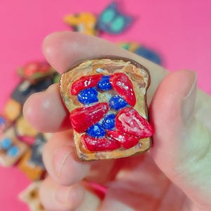 Köstlicher französischer Toast-Magnet aus Ton mit frisch geschnittenen Erdbeeren und Blaubeeren, die mit Puderzucker und beträufeltem Ahornsirup bestreut sind
