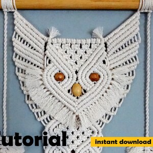Peut inclure: Une suspension murale en macram&eacute; en forme de hibou blanc avec des perles en bois pour les yeux. Le hibou est suspendu &agrave; une baguette en bois. Le texte "Tutoriel t&eacute;l&eacute;chargement instantan&eacute; pdf" est en bas de l'image.