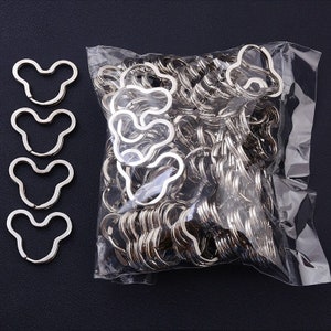 May include: A bag of silver metal keychains shaped like a cartoon bear head. There are four individual keychains on the left side of the image.