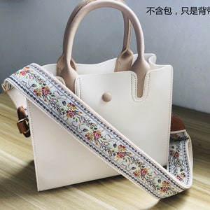 May include: White leather handbag with a floral patterned strap. The strap is removable and can be used as a shoulder strap. The text on the image says "Not included, only the strap".