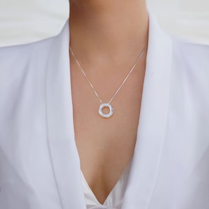 May include: A silver necklace with a circular pendant made of multiple intertwined rings.