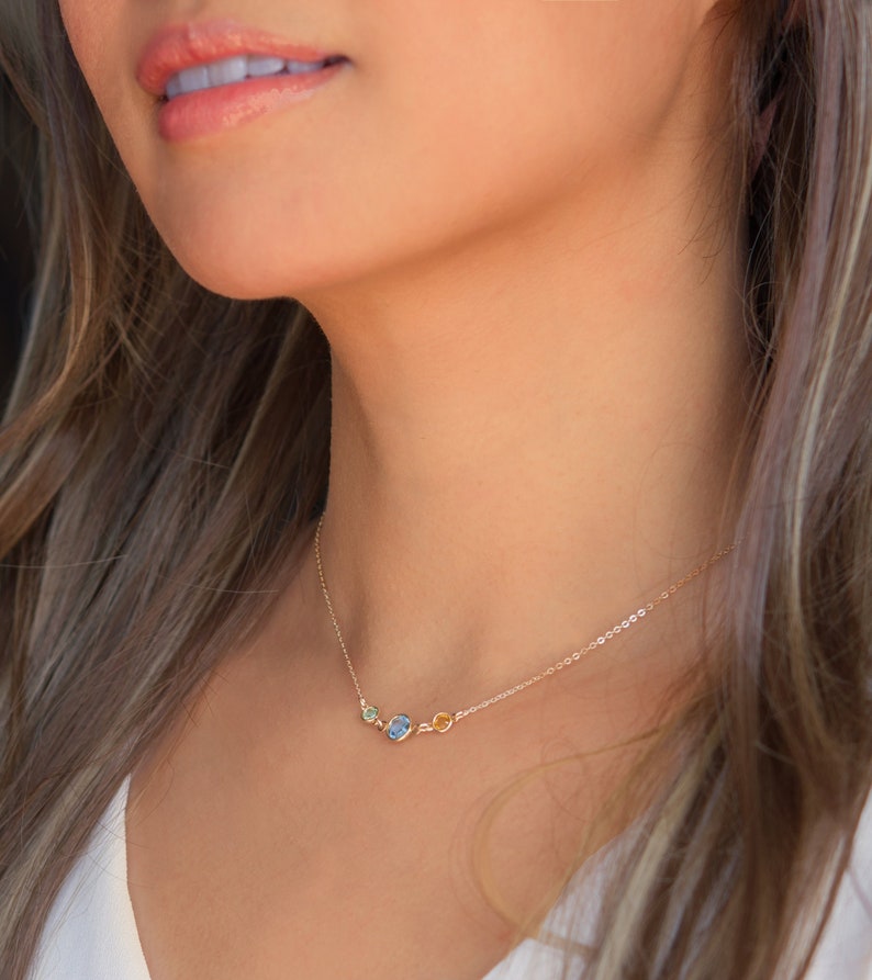 Peut inclure: Un collier en cha&icirc;ne dor&eacute;e avec trois petites pierres ovales. Les pierres sont vertes, bleues et jaunes.