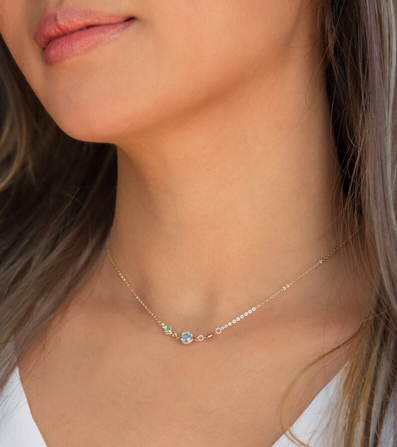 Peut inclure: Un collier en cha&icirc;ne dor&eacute;e avec trois petites pierres rondes. Les pierres sont bleu clair, bleu fonc&eacute; et vert clair.