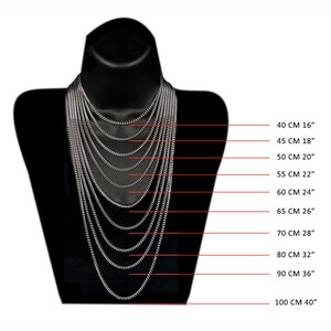 Peut inclure: Un tableau montrant diff&eacute;rentes longueurs de cha&icirc;ne en pouces et en centim&egrave;tres. Les longueurs de cha&icirc;ne vont de 16 pouces &agrave; 40 pouces. Le tableau est affich&eacute; sur un mannequin noir.