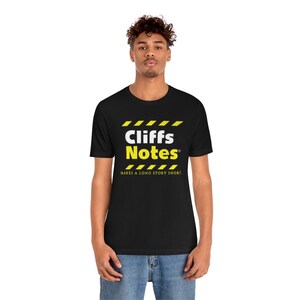 May include: Black t-shirt with a white graphic of the words "Cliffs Notes" in yellow caution tape stripes. The text below the graphic reads "Makes a long story short."