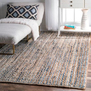 May include: A blue and beige striped jute rug with a woven texture. The rug is placed on a wooden floor in a living room setting.