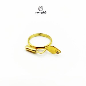May include: A gold ring with a small diamond set in a trowel design. The ring is made by the company "nymph&eacute;".