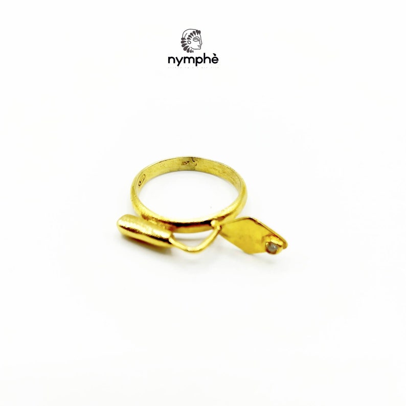 May include: A gold ring with a small diamond set in a trowel design. The ring is made by the company "nymph&eacute;".