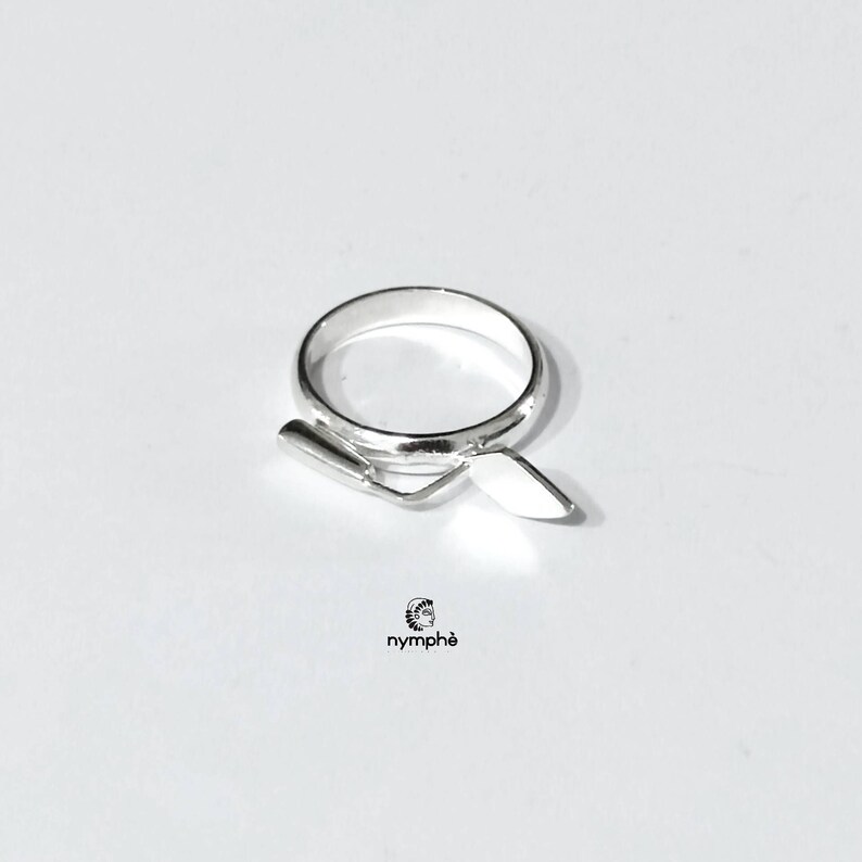 May include: A silver ring with a trowel design. The ring is simple and elegant.