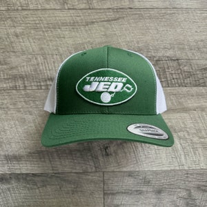 May include: Green and white trucker hat with a white embroidered oval patch that says "Tennessee JED's" with a chain and ball hanging from the bottom of the oval.
