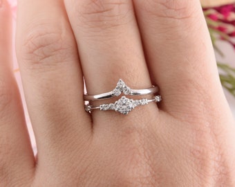 May include: A set of two silver rings with small clear stones. The rings are stacked on each other on a finger.