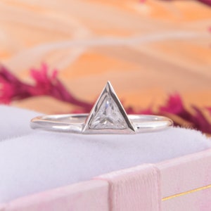 May include: A silver ring with a triangular shaped diamond set in the center.
