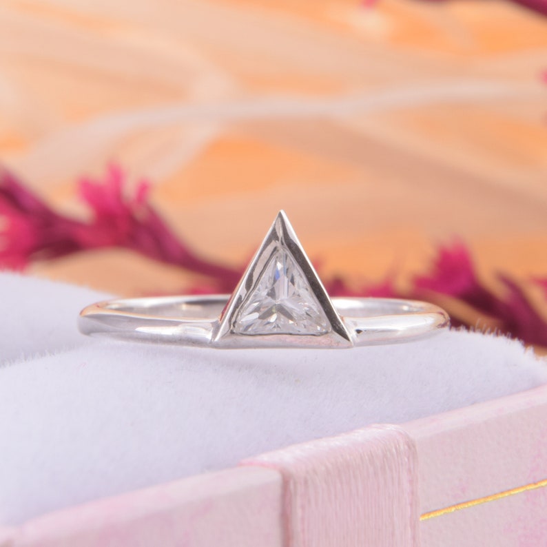 May include: A silver ring with a triangular shaped diamond set in the center.