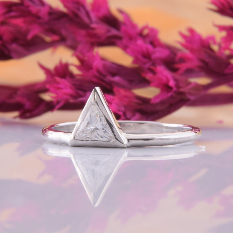 May include: A silver ring with a triangular shaped clear gemstone.