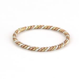 May include: A thin, twisted ring made of silver, gold, and rose gold.