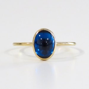 May include: A gold ring with a blue oval gemstone.