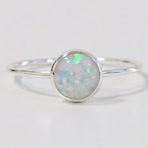 May include: A silver ring with a white opal gemstone. The opal has a subtle iridescent shimmer.