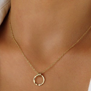 May include: A gold chain necklace with a hammered circle pendant.