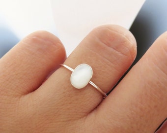 May include: A silver ring with a white oval-shaped gemstone.