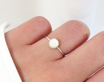 May include: A simple silver ring with a white round gemstone.