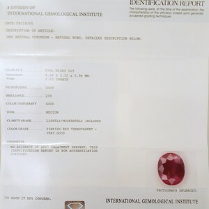 May include: An International Gemological Institute report details a natural ruby. The oval mixed-cut gemstone is described with measurements of 6.58 x 5.52 x 2.96 mm and a weight of 1.03 carats. The report includes color and clarity grades.