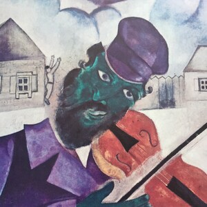 Può includere: Un dipinto di un uomo che suona il violino. Indossa un cappello viola e una giacca viola. Il suo viso è verde e ha la barba. Lo sfondo è azzurro con nuvole e una piccola casa.