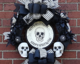 May include: Black and white Halloween wreath with a black and white striped bow, black and white skull design, and the text "Happy Halloween".