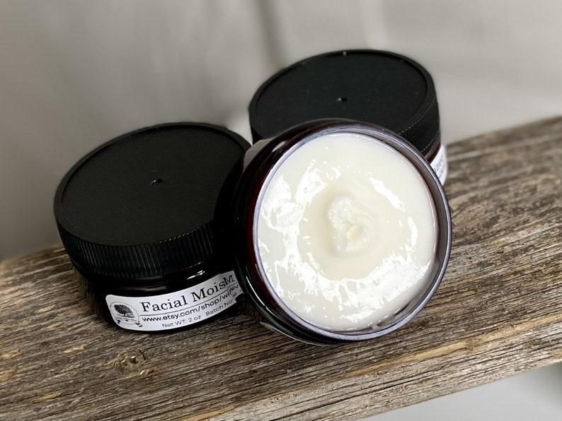 May include: Three small jars of facial moisturizer with black lids. One jar is open, revealing a creamy white product. The jars are labeled "Facial MoistM" and "Net WT. 2 oz."