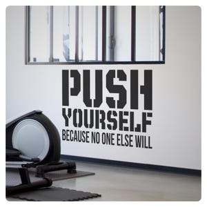 May include: Black and white motivational quote wall decal that reads "PUSH YOURSELF BECAUSE NO ONE ELSE WILL". The decal is displayed on a white wall in a gym setting.