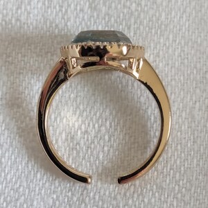 Pu&ograve; includere: Un anello color oro con una grande pietra preziosa azzurra. La pietra, di forma ovale, &egrave; incastonata in una montatura decorativa. Il gambo dell'anello &egrave; aperto in basso.