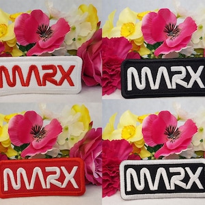 May include: Four embroidered patches with the word "MARX" in a stylized font. The patches are white, black, red, and black with white lettering. The patches are surrounded by pink and yellow flowers.