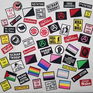 Pu&ograve; includere: Una collezione di toppe ricamate colorate con messaggi politici e sociali. Le toppe presentano slogan come "Tax the Rich", "Revolution", "Scrap Trident", "Kill the Bill", "Don't Vote Tory", "Black Lives Matter", "Free Assange", "Solidarity", "Socialism", "Capitalism", "Tories Out", "Anti-Capitalist Socialist Club", "I am a Free Man, I am not a Number", "Fuck the Tories", and "Don't Buy the Sun".