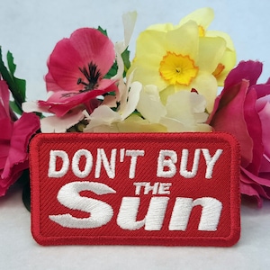 May include: Red embroidered patch with white text that reads "DON'T BUY THE SUN".
