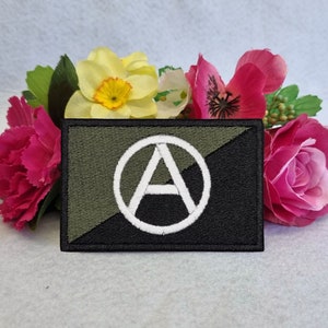 May include: A black and green embroidered patch with a white anarchy symbol in a circle.