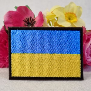 May include: An embroidered patch of the Ukrainian flag, featuring blue and yellow colours with a black border.