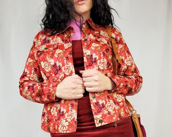 Könnte beinhalten: Eine rote Jeansjacke mit floralem Muster, ein burgunderfarbener Cordrock und schwarze Netzstrümpfe.
