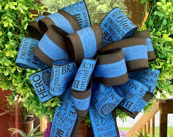 May include: A blue and brown ribbon wreath with the words "Protect & Serve", "Hero", "Blue Enforcer", "Peace Maker", "Brave", "Proud", and "Love" printed on it.