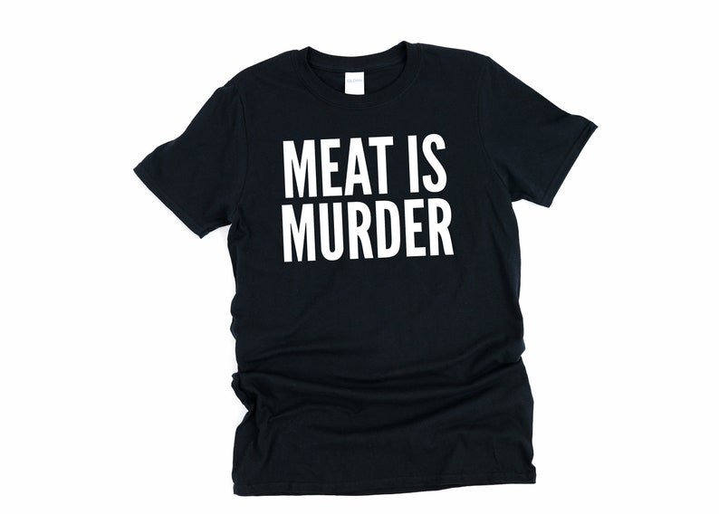 Puede incluir: Camiseta negra con el texto blanco "MEAT IS MURDER". La camiseta de cuello redondo est&aacute; hecha de un material suave. El texto est&aacute; centrado en la parte delantera de la camiseta.