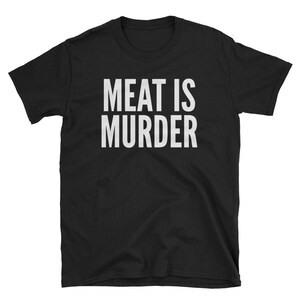Puede incluir: Camiseta negra con el texto blanco "MEAT IS MURDER" en negrita, con fuente sans-serif. La camiseta tiene mangas cortas y cuello redondo. El texto est&aacute; centrado en la parte delantera de la camiseta.