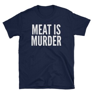 Puede incluir: Camiseta azul marino con el texto blanco "MEAT IS MURDER" en una fuente en negrita sin serifa. La camiseta, de manga corta y cuello redondo, probablemente est&aacute; hecha de algod&oacute;n o un tejido similar, y se muestra sobre un fondo blanco.