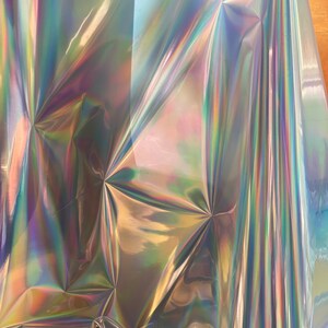 Op de afbeelding: Een vel iriserend holografisch vinyl met een regenboogkleurige glans. Het vinyl is gekreukt en gevouwen, waardoor een textuur ontstaat.