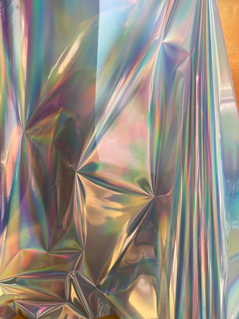 Op de afbeelding: Een vel iriserend holografisch vinyl met een regenboogkleurige glans. Het vinyl is gekreukt en gevouwen, waardoor een textuur ontstaat.