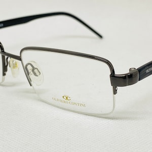 May include: A pair of black metal frame spectacles with clear lenses. The brand name "Oliviero Contini" is printed on the frame.