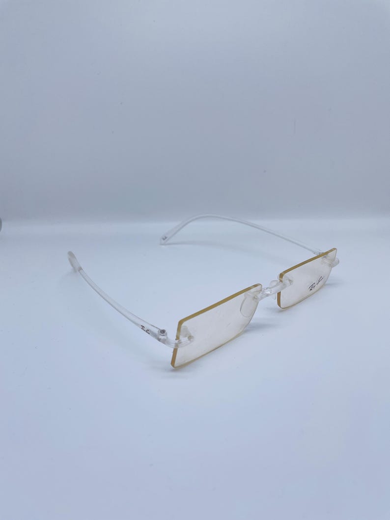 May include: Clear plastic frame glasses with a rectangular lens shape. The glasses have a subtle gold tint.