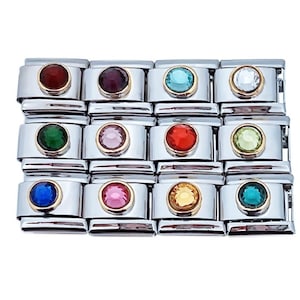 May include: A set of 12 colorful charm links for a charm bracelet. Each link features a different colored crystal stone in a silver setting.