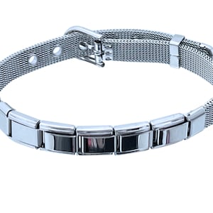 May include: A silver bracelet with a mesh band and a clasp closure. The bracelet has a row of small, rectangular charms.