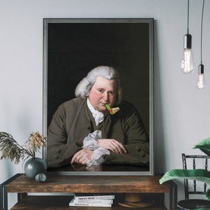 May include: A framed portrait of a man in a dark brown jacket with a white shirt and a green and yellow party blower in his mouth. The portrait is set against a dark background.