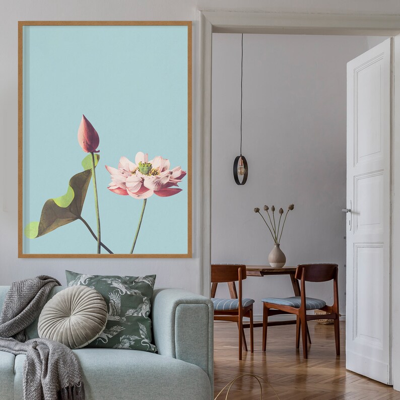 May include: A framed print of a pink lotus flower with a bud on a light blue background.